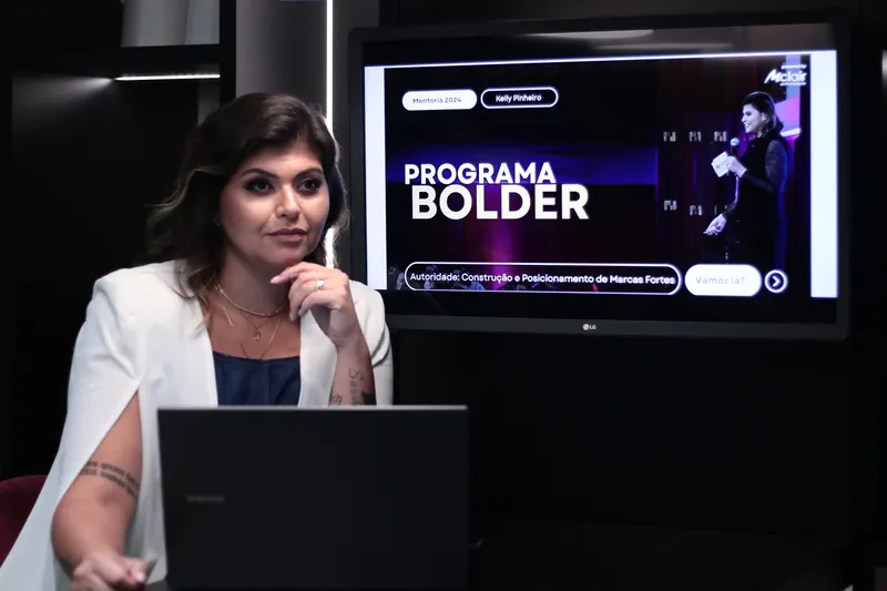 Kelly Pinheiro conduzindo um encontro de mentoria, com a tela do Programa Bolder ao fundo